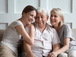 Cheerful three-generation family sitting on couch enjoy time together